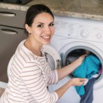 kobieta wklada ubrania do pralki